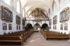 Das Kloster Schönau wurde zum Ende des 12. Jahrhunderts gegründet. Doch das barocke Ensemble geht auf die  Würzburger Kapuziner-Minoriten zurück, die 1699 das Kloster übernommen haben. Der Thüngersheimer Maler Georg Sebastian Urlaub schuf die bis heute erhaltene reiche Gemäldeausstattung in Kirche und Mönchchor. Die Bilder der Kreuzwegstationen wurden 2018 restauriert. 