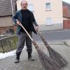 Reinhold Müller mit zwei verschiedenen von ihm hergestellten Reisigbesen.
