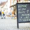 Lachen als Mittel gegen Corona. "Humor ist die beste Medizin und Kuchen" stand auf einem Plakat vor einer Bäckerei in Haßfurt zu lesen. 