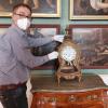 Das Foto zeigt den Restaurator Michael Bronold bei der Aufstellung der Uhr im Bilderzimmer.