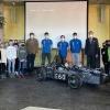 Schülerinnen und Schüler der 5. Jahrgangsstufe mit Lehrer Ansgar Freking, drei Teammitgliedern des Formula Student Teams, in der Mitte Fabian Kleinlein, Schulleiter Achim Höfle und weiteren Schülerinnen und Schüler der 5. Jahrgangsstufe sowie dem Rennwagen.