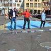 Der 3D-Effekt ist schon erkennbar: Das fertige Straßengemälde wird später eine Schlucht mit Brücke zeigen. Verkehrsdirektor Kersten Hahn (links) und Svenja Schuck (rechts) vom städtischen Kulturamt hießen Street Artist Marion Ruthardt in Bad Mergentheim willkommen.