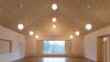 Der große Saal ist mit hellem Holz und einem Panoramafenster mit Blick ins Grüne ausgestattet.