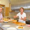 Heute gibt es leckere Pizza und Irmgard Reß (rechts)holt die Bleche aus dem Ofen. Die Stücke werden von Isolde Herold ofenfrisch serviert.