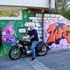 Älter als er selbst, ist seine Triumph, mit der sich Manfred Jung hier vor seinem Lieblingsgraffiti des Jugendlichen "Wesam" (rechts) am Aufgang zum Jugendtreff postiert hat