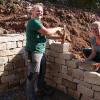 Trockenmauern setzten Gartenplaner zur modernen Gestaltung des "Wohlfühlplatzes" ein. Während Azubi Svenja Pfeifroth (links) mit Hammer und Meißel die Steine bearbeitet, setzt Vorarbeiterin Alina Burdik das Mauerwerk.