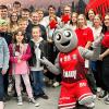 Olli begrüßt Pfarrer Adam Was (rechts) und die Ministranten der Pfarrei St. Veit, Iphofen beim Basketball Bundesligaspiel in der tectake Arena in Würzburg.