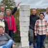 Teilnehmer des Bildhauerworkshops, im Vordergrund sitzend der Kleinrinderfelder Bildhauer Kurt Grimm.Die Stele ist das Ergebnis des gemeinsamen Arbeitens.