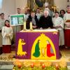 Weihnachtliche, frohe Stimmung in der Kirche St. Vitus in Hörblach.  In die Mitte genommen haben Ministranten aus sechs Jahrzehnten Altardienst ihren Küster Alois Fröhling und seine Frau Viktoria bei der Überreichung der Goldmedaille des Mesnerverbandes des Bistums, der Ehrenurkunde von Bischof Franz Jung und einer Dankbotschaft der Hörblacher Kirchengemeinde sowie eines Geschenkkorbes, den Anna Kram dem Jubilar überreichte.