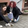 Annalena Mohr und Nele Hüsam reinigen die Stolpersteine und legen Rosen nieder.