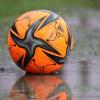 Ein Ball liegt auf einem Sportplatz in einer Pfütze. Durch teils ergiebige Niederschläge an den vergangenen Tagen sind zahlreiche Fußballplätze in der Region unbespielbar.