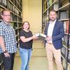 Registrator Daniel Herberich (links) und der Leiter des Fachbereichs Zentrale Dienste und Vergabestelle André Feil (rechts), übergeben Sabrina Greß (Mitte) von der Lebenshilfe Schweinfurt symbolisch den ersten Aktenordner. In den kommenden Monaten werden weitere Hunderte zur Aufarbeitung und Digitalisierung folgen.