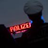 Zwei Polizisten stehen vor einem Polizeifahrzeug.