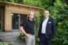 Norbert Beck vom Heim Sankt Joseph (links) und Alexander Weigand vom Rotary Club Würzburg-Stein vor dem neu erbauten Gartenhäuschen in Würzburg am Spittelbergweg.