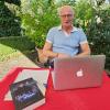 Hubert Ziegler alias Orlando Stein in seinem Garten, wo er am Laptop schreibt. Vor ihm sein Debüt-Roman: "Bulle und Finn".