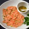 Wenn man das Lachs-Carpaccio mit dem asiatischen Dressing beträufelt, wird die Farbe des Fischs etwas heller.