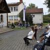 Der ökumenische Kirchweihgottesdienst fand vor der Christuskirche im Freien mit den „Unterlangenstadter Blechbläsern“ (hinten, li.) sowie Pfarrer Daniel Steffen Schwarz und Pastoralreferent Johannes Haaf (am Kircheneingang) statt.