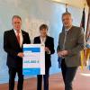 Wirtschaftsstaatssekretär Roland Weigert (re.) übergibt den Förderbescheid an die Vorsitzenden von Oberfranken Offensiv, Regierungspräsidentin Heidrun Piwernetz und Bezirkstagspräsident Henry Schramm.