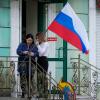 Frauen hängen im September 2022 eine russische Flagge in ihrem Geschäft in Luhansk auf.