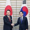 Südkoreas Präsident Yoon Suk Yeol (l.) und Japans Premier Fumio Kishida reichen sich vor ihren Gesprächen die Hände.
