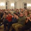 Ist es Kabarett? Oder ein klassisches Konzert? Oder am Ende irgendwo irgendetwas dazwischen? Die Grenzen verlaufen fließend, wenn Lizzy Aumeier mit ihren „Weißen Lilien“ die Bühne betritt. So auch am Dreikönigstag, als sie mit ihren Damen im gut besuchten Kaisersaal nach langer Abstinenz wieder ihr Neujahrskonzert spielen konnte.  Begann es als Therapiesitzung, angekündigt durch den Leiter der „Anstalt“, Siegmund Freud, betraten die Damen in Morgenmänteln die Bühne. Natürlich durfte ein Corona-Rückblick nicht fehlten. So debattierte man über die Zeit des Lockdowns und stellte die Frage, ob denn nicht der ein oder andere während dieser Zeit zu- oder abgenommen, und wer an Scheidung oder Mord gedacht habe. Musik sei eine Therapie, denn man lebt sie nach außen, war das Fazit. Auch die Impfgegner wurden zum Ziel. So erzählte Lizzy Aumeier, eine Freundin von ihr, die sich vor Corona die Brüste habe vergrößern lassen, wollte sich nicht impfen lassen. „Ich will nix künstliches in meinem Körper.“ Doch die Gags wirkten allgemein etwas müde. Das lag vielleicht auch darin begründet, dass man für die musikalischen Teile weder Mikrofone noch Verstärker oder sonstige Elektronik brauchte, für die Zwischenstücke man die Damen allerdings oft nur sehr schwer verstehen konnte.  Immer, wenn sie zu ihren Instrumenten griffen, dann wurden die Stärken des Ensembles deutlich sicht- und hörbar. Thema des musikalischen Teils war das Wirken von Christoph Willibald Gluck, der 1714 in der Oberpfalz geboren wurde und als einer der bedeutendsten Opernkomponisten in der zweiten Hälfte des 18. Jahrhunderts gilt. Das Ensemble gab einige der bedeutendsten Werke Glucks zum Besten, darunter „Reigen seliger Geister“ und „Ach, ich habe sie verloren“ aus der Oper „Orpheus und Eurydike“,  Doch auch andere Stücke wurden in der Interpretation der „Weißen Lilien“ dargeboten, darunter ein Medley, das so bekannte Stück wie „Fever“ (im Original von Little Willie John gesungen), „All time high“ von Rita Coolidge, dem Titelsong aus dem Bond-Film „Octopussy“, „Isn´t she lovely“ von Stevie Wonder und „Ain´t no mountain high enough“ von Marvin Gaye. Hier zeigte sich auch die Klasse des Ensembles.  Geführt von Svetlana Klimova, der ehemaligen Konzertmeisterin der Moskauer Symphoniker an der Violine, zeigten Alice Graf am Flügel, Gaby Athmann an der Flöte, Baroness Irene von Fritsch am Violoncello und Lizzy Aumeier am Kontrabass ihre Stärke. Harmonisch und virtuos zogen sie das Publikum in ihren Bann.  Die größten Lacher indes zog Andreas Stock, Lizzy Aumeiers Ehemann, auf sich. Trat er am Anfang und zwischendurch als Therapeut auf, so verkörperte er nach der Pause, als die Damen in Abendgarderobe auf die Bühne traten, jenen Christoph Willibald Gluck. So erzählte er, dass er ja Champagner liebe, aber nicht wegen des Geschmacks. Einer Legende nach wäre die Champagnerschale den Brüsten Marie Antoinettes nachempfunden. Und das gäbe dem Genuss eine besondere Form.  Einen Texthänger überspielte er, als er fragte: „Soll ich noch was sagen oder kann ich gehen?“, woraufhin Lizzy Aumeier konterte: „Hast du deinen Text vergessen? Du weißt aber noch, dass wir seit 25 Jahren verheiratet sind?“ Diese Szene wirkte wie ein Improvisationstheater, was Lachstürme und spontanen Szenenapplaus zur Folge hatte.  Es wurden vor und nach der Pause diverse Lebensstationen Glucks erwähnt, so seine Zeit in London und Wien. Er habe, so Aumeier, seine Inspiration zum großen Teil aus der Natur bezogen. Passend dazu spielten die Damen „Hijo de la Luna“ von José Maria Cano.  Auch die Lebensumstände während der Zeit Glucks waren Thema, so unter anderem die Bekleidung. Es wurde über die Männer- und Damenmode referiert, dass die Damen Korsetts trugen und die Männer Hemden als Unterhemden. Und des Nachts trug man Mützen, um den Kopf vor der Kälte zu schützen. Passend dazu erklang „Mister Sandman“ aus dem Jahr 1954.  Mit einem Nachtlied ging das Programm zu Ende. „Eine kleine Nachtmusik“ von Wolfgang Amadeus Mozart mit Einschüben bekannter Lieder wie „A hard days Night“ von den Beatles oder „Stranger in the Night“ bildete den Abschluss, was das Publikum allerdings nicht akzeptierte, und so folgte „Can Can“ des Komponisten Jacques Offenbach, was die Besucherinnen und Besuchern zu Beifallsstürmen hinriss.  Mit dem Abendsegen aus „Hänsel und Gretel“ von Engelbert Humperdinck, Blumen für die „Lilien“ und Bier für Andreas Stock endete dann eine Vorstellung, die allerdings auch von einigen Gästen kritisiert wurde. Dabei ging es in der Hauptsache um die Wahl des Veranstaltungsortes. So schön und edel das Ambiente auch sein mochte, so der Tenor, für Gehbehinderte ist er wenig geeignet. Die lange Rampe bis zum Eingang, die bei Nässe oder Glatteis für Menschen mit Gehbehinderungen kaum zu meistern ist, sowie die vielen Treppen bis zum Kaisersaal standen dabei im Mittelpunkt.  Mag sein, dass es eine schöne Tradition ist, das Neujahrskonzert dort abzuhalten. Doch stellt sich die Frage, ob viele Interessierte aufgrund der Schwierigkeiten beim Betreten des Veranstaltungsortes bereits im Vorfeld auf einen Besuch verzichten.