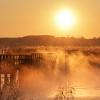 Wetter in Baden-Württemberg: Ein Mann fotografiert kurz nach Sonnenaufgang auf dem 1,5 Kilometer langen Federseesteg den Federsee.
