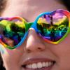 Eine Person, die eine Sonnenbrille mit Regenbogenherz trägt, beobachtet die World Pride Parade in Washington.