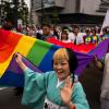 Pride-Marsch in Tokio: Menschen tragen eine Pride-Flagge, während sie am Pride-Marsch in Tokio teilnehmen.