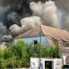 Auf dem alten Schlachthofgelände in Erfurt ist ein Feuer ausgebrochen und Rauch steigt in den Himmel, während die Feuerwehr gegen die Flammen kämpft.