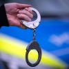 Handschellen vor einem Polizeiauto (Symbolbild).