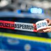 Eine Polizistin rollt ein Absperrband aus. Eine Polizistin rollt ein Absperrband aus.