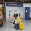 Eine Frau sitzt vor dem Testzentrum am Flughafen von Palma de Mallorca auf Koffern.