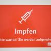 Ein Schild mit der Aufschrift "Impfen - Bitte warten! Sie werden aufgerufen." ist in einem Impfzentrum angebracht. Ein Schild mit der Aufschrift "Impfen - Bitte warten! Sie werden aufgerufen." ist in einem Impfzentrum angebracht.