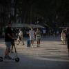 Menschen, manche von ihnen mit Mundschutz, gehen auf der langen Promenade La Rambla in Barcelona entlang.
