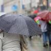 Passanten mit ihren Regenschirmen bei einem kräftigen Regenschauer.