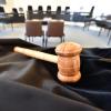Auf einem Tisch liegt ein Richterhammer, darunter liegt eine Richterrobe.