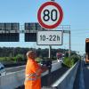 Mitarbeiter der Autobahnmeisterei stellt Schilder für ein Tempolimit auf.