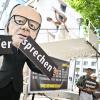 Ein Aktivist mit Merz-Maske zerbricht während einer symbolischen Protestaktion von Kabul Luftbrücke und Campact ein Schild mit der Aufschrift «Versprechen».