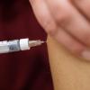 Eine Arzthelferin impft eine Patientin mit einer Spritze.
