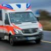 Ein Rettungswagen mit Blaulicht fährt über eine Straße.