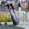 Aus einem Brunnen in der Innenstadt ragen zwei Beine mit Gummistiefeln einer Installation hervor. Foto: Uli Deck
