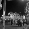 1967: Abendaufnahme mit Riesenrad und Fahrgeschäften während des Betriebs. 1967: Abendaufnahme mit Riesenrad und Fahrgeschäften während des Betriebs.