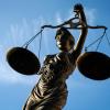 Eine Statue der Justitia hält eine Waage in ihrer Hand.