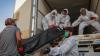 Arbeiter in Schutzkleidung beladen in Bagdad einen Kühlwagen mit Leichen von Menschen, die am Coronavirus gestorben sind.