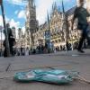 Eine getragene Mundschutzmaske liegt in der Münchener Innenstadt auf dem Gehweg. In der bayerischen Landeshauptstadt gelten ab Donnerstag verschärfte Kontaktbeschränkungen sowie eine generelle Maskenpflicht in Teilen der Altstadt.