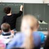 Eine Lehrerin schreibt in einer Schule an die Tafel.