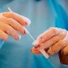 Eine Pharmazeutin in einer Schnelltest-Station einer Apotheke mit einem Corona-Teststäbchen. Eine Pharmazeutin in einer Schnelltest-Station einer Apotheke mit einem Corona-Teststäbchen.
