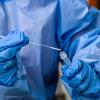 Eine Krankenschwester steckt ein Abstrichstäbchen in die Flüssigkeit eines Corona-Schnelltests.