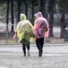 Menschen mit Plastik-Regenschutz gehen durch den Regen.