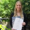 Sabrina Seitz vom Betrieblichen Gesundheitsmanagement des Uniklinikums Würzburg präsentiert die Urkunde und den Getränkegutschein, die den UKW-Radlern für den ersten Platz in der Kategorie „Unternehmenswettbewerb“ des Stadtradelns überreicht wurden.